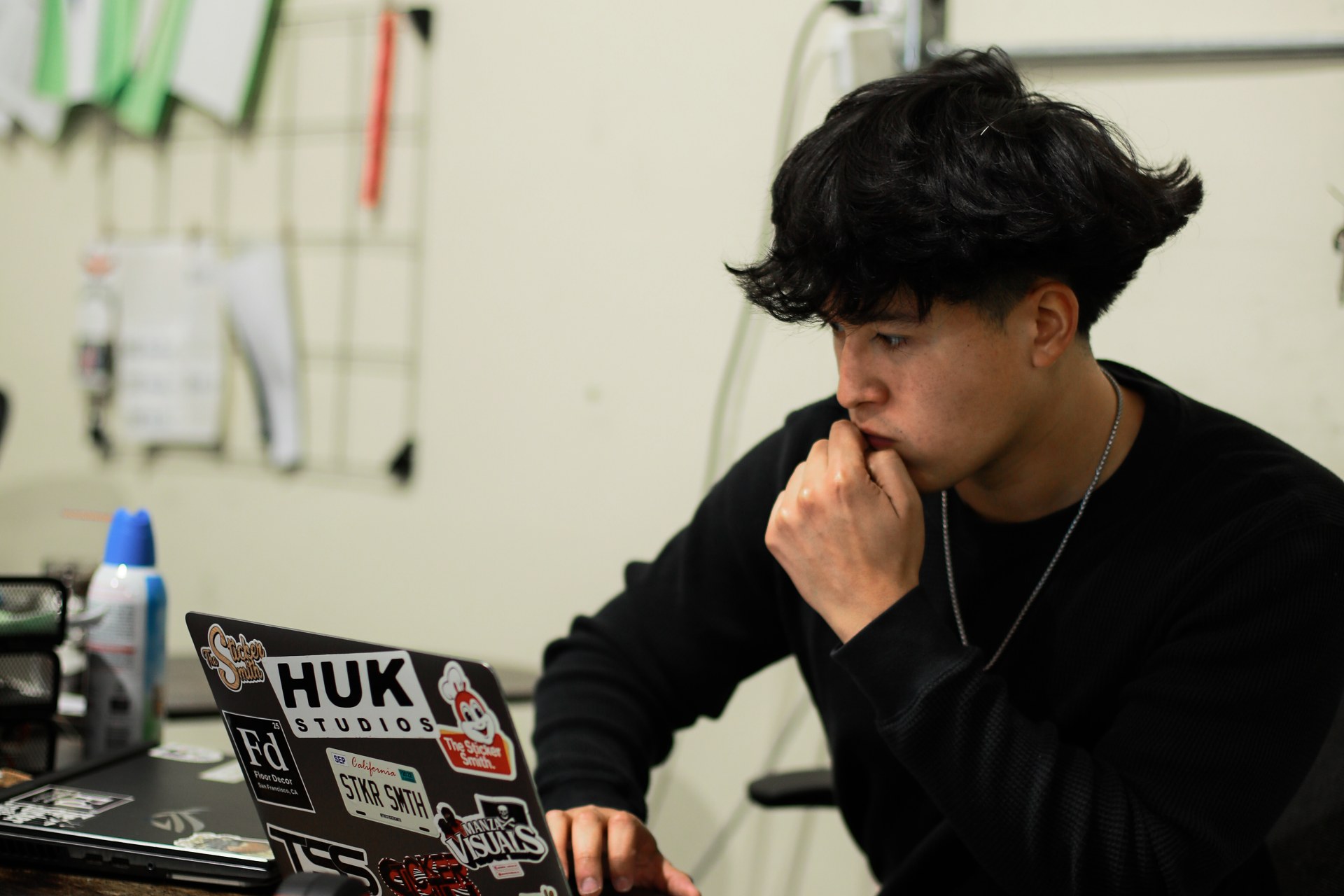 Jordan Lopez at his desk, working on a laptop covered in client stickers