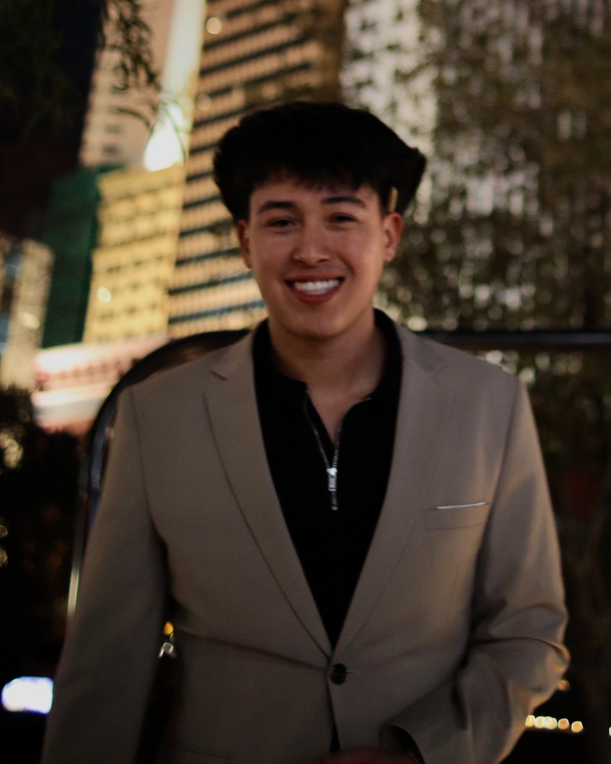 Jordan Lopez smiling outdoors at night in a light blazer